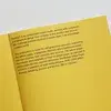 Open yellow book with text about an independent brand studio, focusing on strategy, brand, product, and service. Contact info for inquiries included.